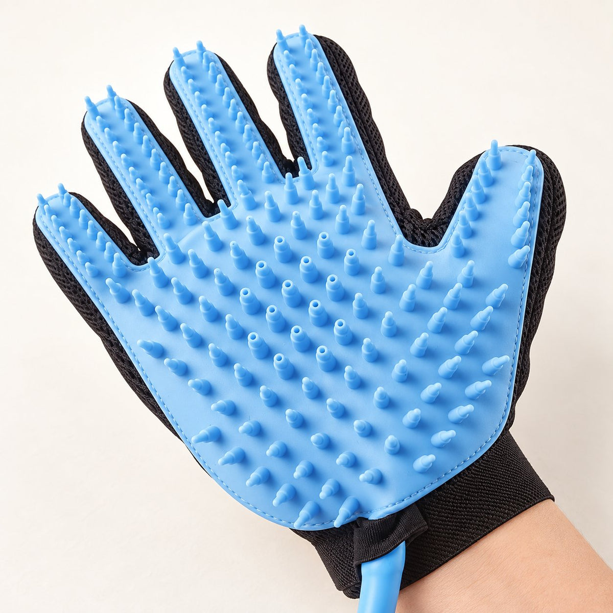 Shower glove worn on a hand, showing the bristles
